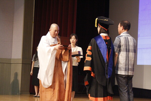 ▲우리대학 이사장 돈관스님이 졸업생들에게 공로상을 수여하고 있다 (사진=오은빈 기자.)